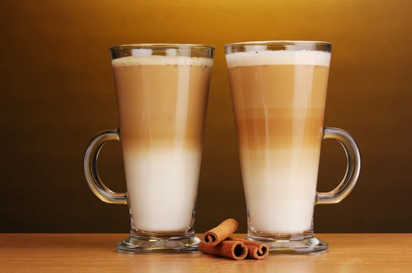 Pachnące? Unduli latte kubki szklane i cynamon na drewnianym stole na brązowe b — Zdjęcie stockowe