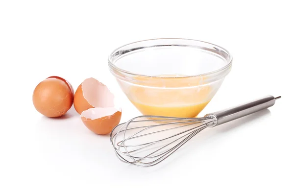 Metal whisk for whipping eggs and eggs in bowl isolated on white — Stock Photo, Image