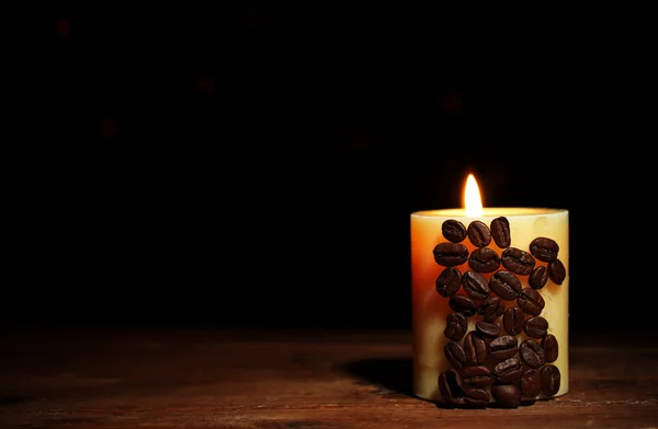 Hermosa vela con granos de café en la mesa de madera sobre fondo negro — Foto de Stock