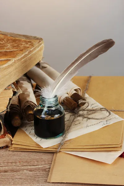 Staré knihy, svitky, peří pero a inkwell na dřevěný stůl na šedé backgro — Stock fotografie