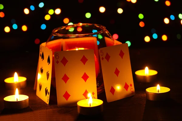 Bougies et cartes à jouer sur table en bois sur fond lumineux — Photo