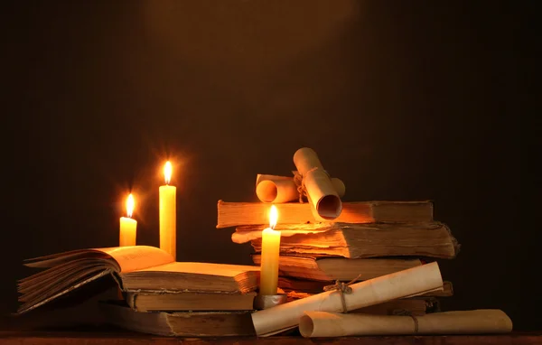 Högen av gamla böcker med ljus och bläddra i mörkret — Stockfoto