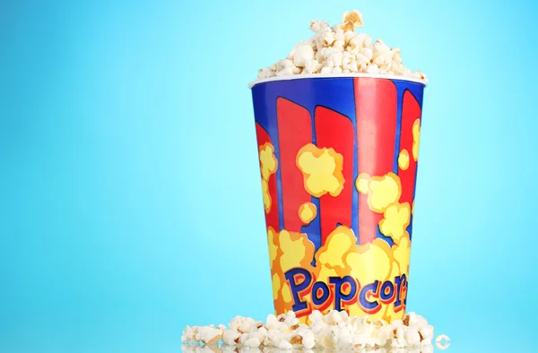 Full bucket of popcorn on blue — Stock Photo, Image