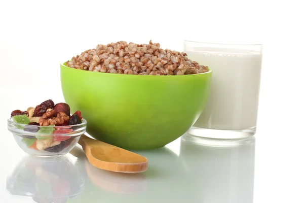 Boiled buckwheat in a green bowl a glass of milk isolated on white — Stock Photo, Image