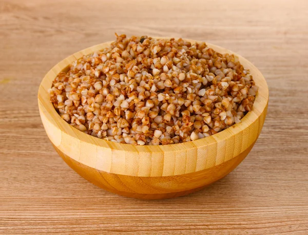 Boiled buckwheat in a wooden bowl on wooden background — Stock Photo, Image