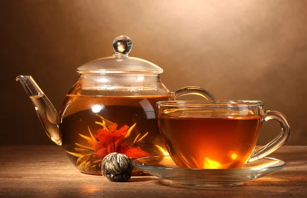 Bule de vidro e xícara com chá verde exótico na mesa de madeira no backgro marrom — Fotografia de Stock