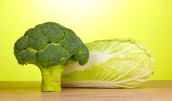 Fresh broccoli and chinese cabbage on wooden table on green background — Stock Photo, Image