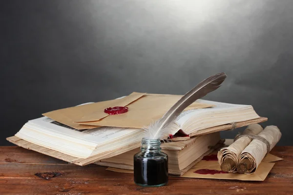 राखाडी बॅकग्रो वर लाकडी टेबलवर जुन्या पुस्तके, स्क्रोल, पंख पेन आणि inkwell — स्टॉक फोटो, इमेज