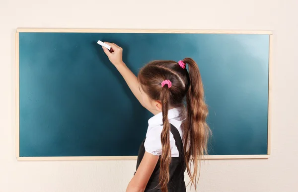 Linda menina escrevendo no quadro de sala de aula — Fotografia de Stock
