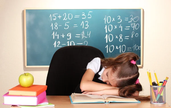 Pequena estudante dormir em sala de aula perto de quadro negro — Fotografia de Stock