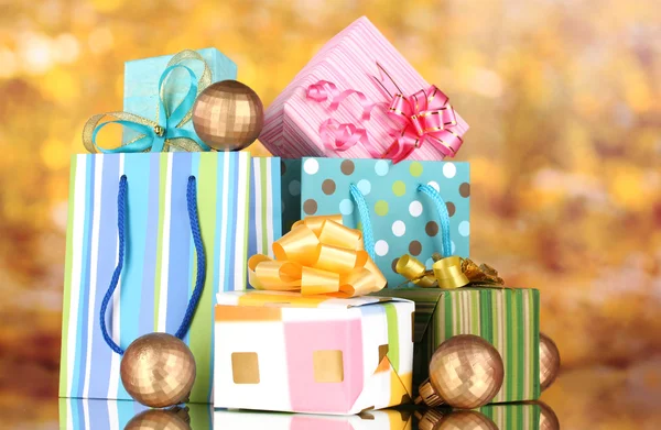 Heldere geschenk zakken en giften op gele achtergrond — Stockfoto