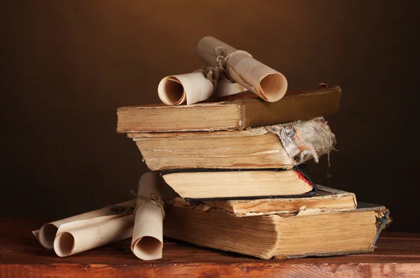 Pile of old books and scroll on brown — Stock Photo, Image