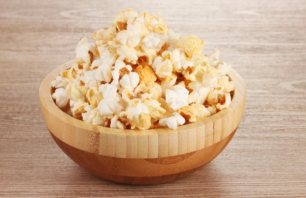 Popcorn in wooden bowl on wooden table — Stock Photo, Image