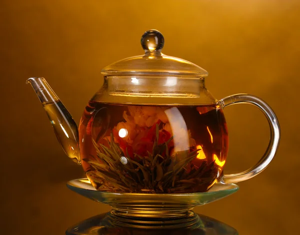 Skleněná konvice s exotickými zelený čaj na dřevěný stůl na hnědé pozadí — Stock fotografie