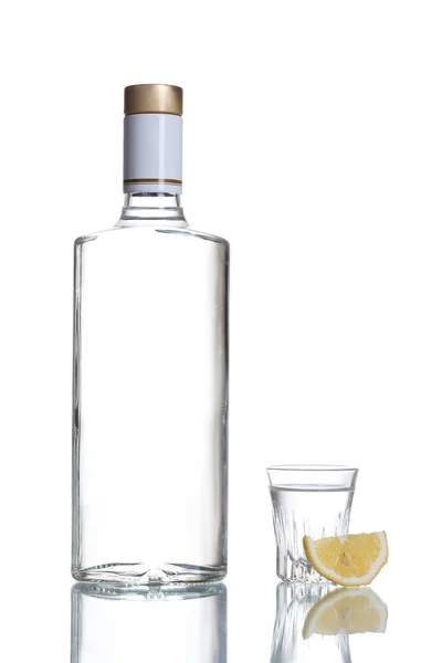 Butelka wódki i lampka z cytryny na białym tle — Zdjęcie stockowe