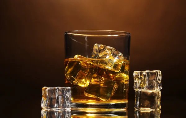 Sklenice whisky a ledu na hnědé pozadí — Stock fotografie