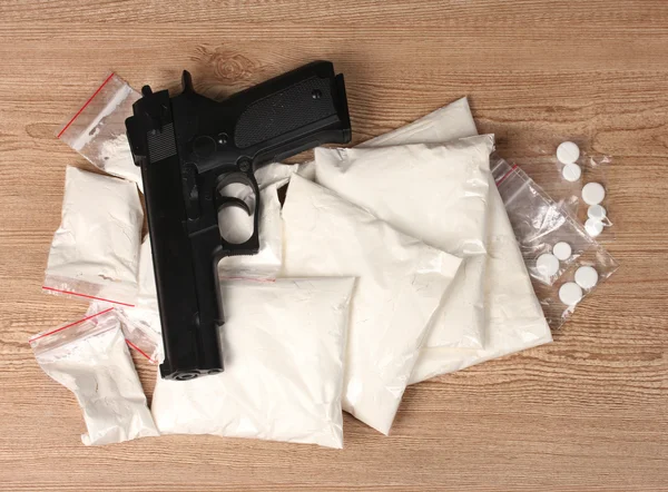 Kokaint és marihuánát csomagok és a pisztolyt a fából készült háttér — Stock Fotó