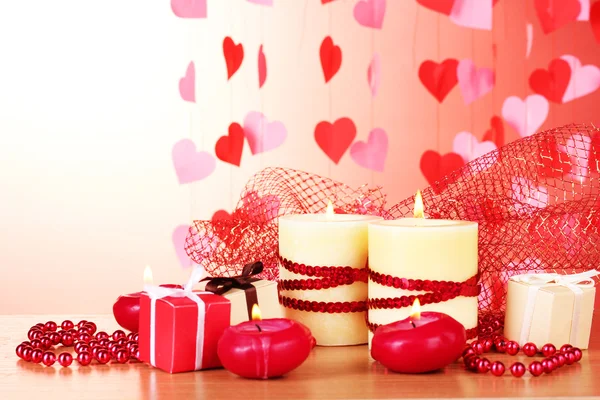 Belle candele con arredamento romantico su un tavolo di legno su sfondo rosso — Foto Stock