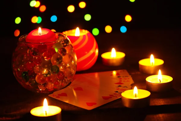 Свечи и игральные карты на деревянном столе на ярком фоне — стоковое фото