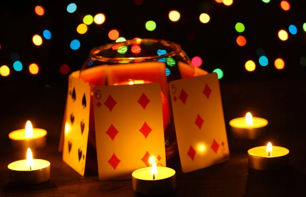 Свечи и игральные карты на деревянном столе на ярком фоне — стоковое фото