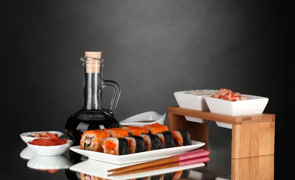 Delicioso sushi en plato, palillos, salsa de soja, pescado y camarones en gris b —  Fotos de Stock