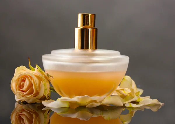 Perfumy dla kobiet w pięknej butelce z róż na szarym tle — Zdjęcie stockowe