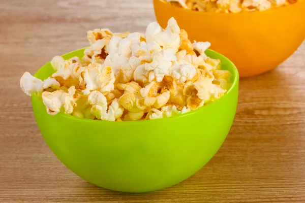 Popcorn in hellen Plastikschalen auf Holztisch — Stockfoto