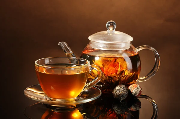 Szklany czajnik i filiżanki z egzotycznych zielonej herbaty na drewnianym stole na brązowy backgro — Zdjęcie stockowe