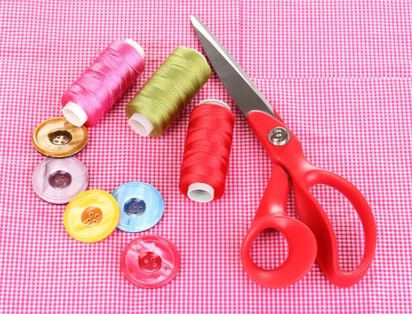Tesoura, botões e fios brilhantes em tecido isolado em branco — Fotografia de Stock