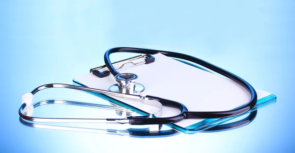 Estetoscopio médico y portapapeles sobre fondo azul — Foto de Stock