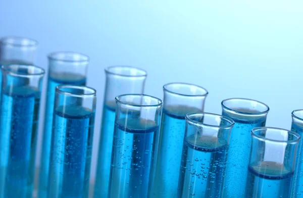 Tubos de ensayo con líquido azul sobre fondo azul — Foto de Stock