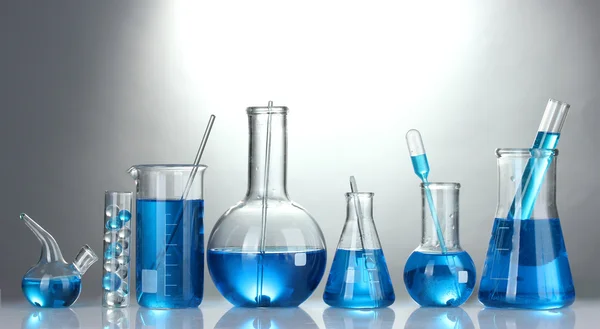 Reagenzgläser mit blauer Flüssigkeit auf grauem Hintergrund — Stockfoto
