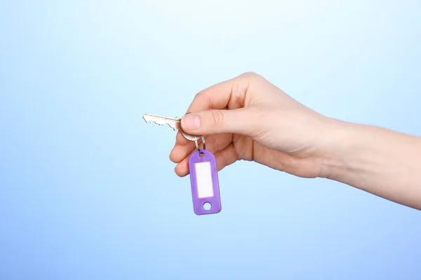 Key in hand on blue background — Stock Photo, Image