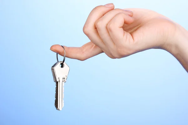 Keys in hand on blue background — Stock Photo, Image