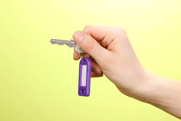 Nyckeln i handen på grön bakgrund — Stockfoto