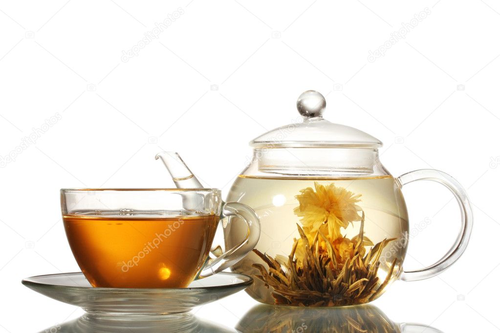 Exotic green tea with flowers in glass teapot and cup isolated on white