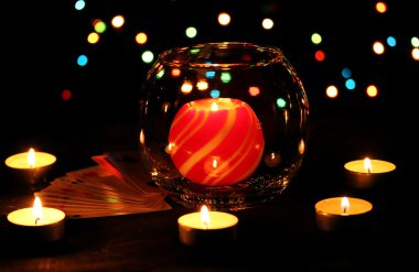 Candles and playing cards on wooden table on bright background clipart