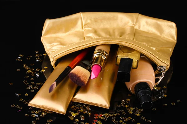 Hermosa bolsa de maquillaje dorado y cosméticos aislados en negro — Foto de Stock