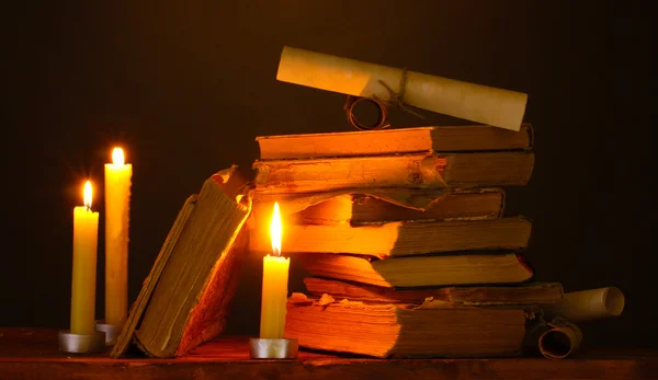 Montón de libros antiguos con vela y pergamino en la oscuridad — Foto de Stock