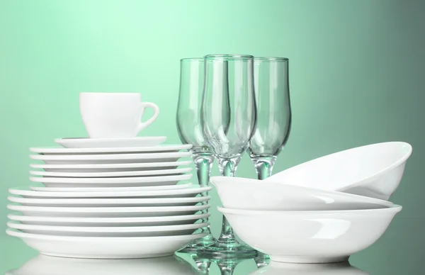 Piatti puliti, tazza e bicchieri su sfondo verde — Foto Stock