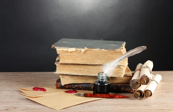 stock image Old books, scrolls, feather pen and inkwell on wooden table on grey backgro
