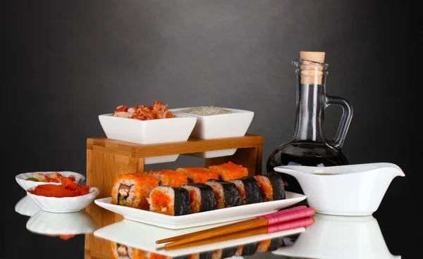 Delicioso sushi en plato, palillos, salsa de soja, pescado y camarones en gris b — Foto de Stock