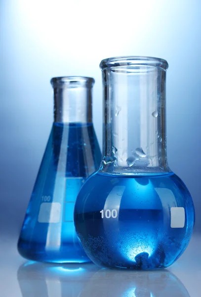 Tubos de ensayo con líquido azul sobre fondo azul —  Fotos de Stock