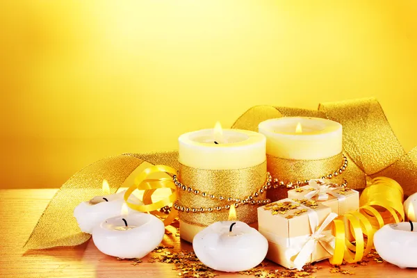Beautiful candles, gifts and decor on wooden table on yellow background Royalty Free Stock Images