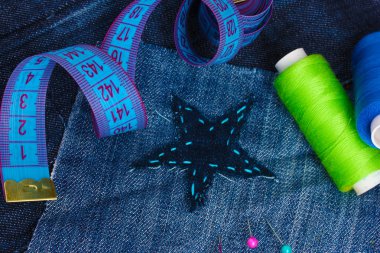 Star-shaped patch on jeans with threads and buttons closeup clipart