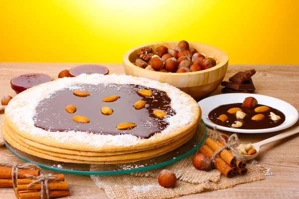 Tårta på glas stå och nötter på träbord på gul bakgrund — Stockfoto