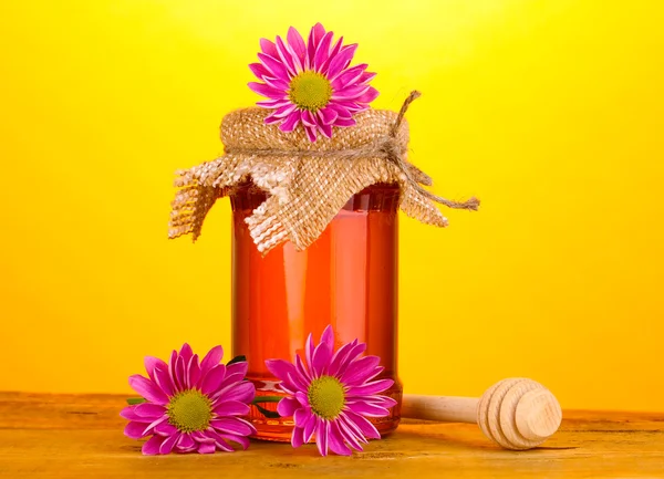 Miel dulce en tarro con rociador sobre mesa de madera sobre fondo amarillo —  Fotos de Stock