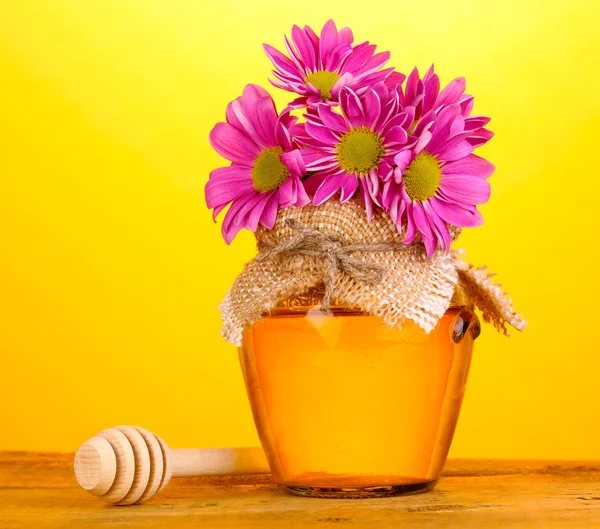 Miel sucré en pot avec drizzler sur table en bois sur fond jaune — Photo