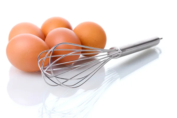 Metallbesen zum Aufschlagen von Eiern und braunen Eiern isoliert auf weiß — Stockfoto