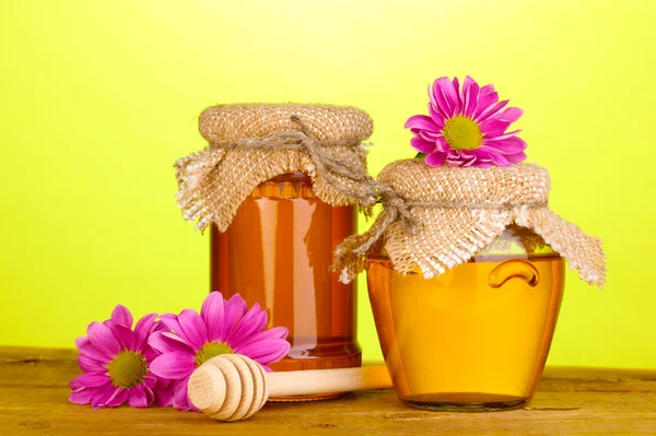 Miel dulce en frascos con rociador sobre mesa de madera sobre fondo verde —  Fotos de Stock